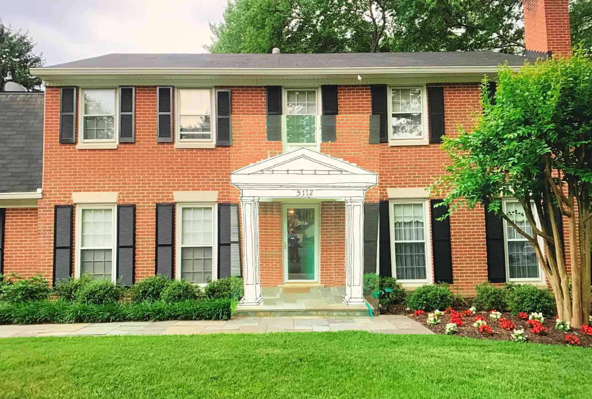 Two-story brick house with white columns and black shutters.