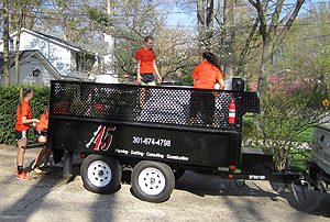 Two people in orange shirts stand on a black trailer during daytime.
