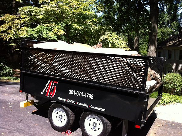 Black trailer with mesh sides parked outdoors on grass.